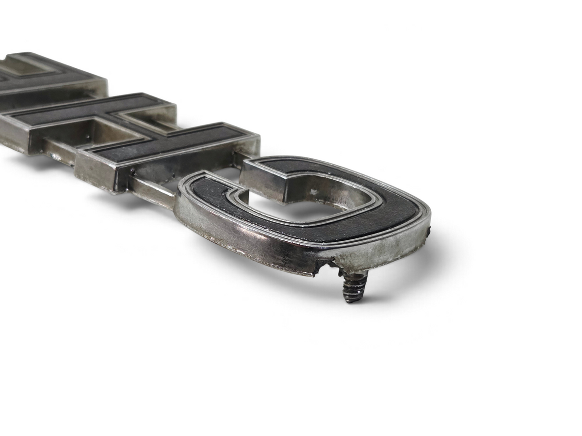 Send it Auto Parts OEM Chevy truck tailgate emblem with black and chrome finish showing minor wear and missing pins